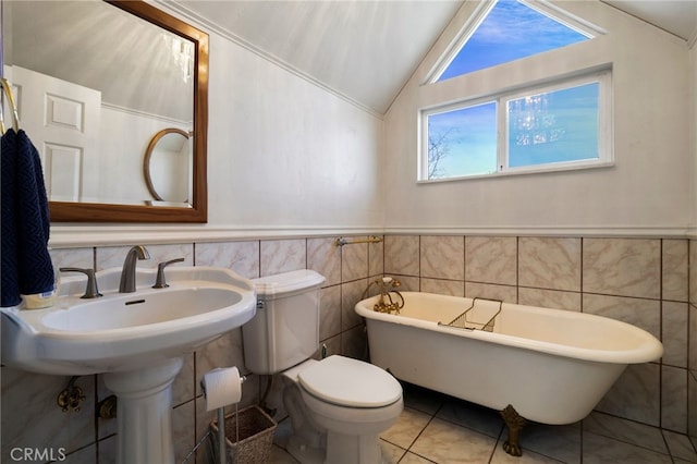 bathroom with vaulted ceiling, tile walls, a tub to relax in, toilet, and tile patterned floors