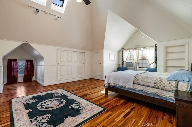 bedroom with hardwood / wood-style flooring, high vaulted ceiling, and a skylight