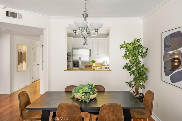 dining space featuring ornamental molding, a chandelier, and light hardwood / wood-style floors