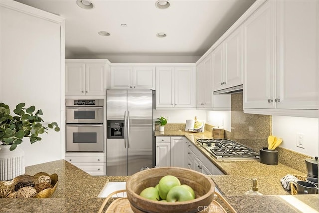 kitchen with appliances with stainless steel finishes, light stone countertops, decorative backsplash, and white cabinets