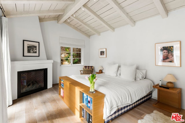 bedroom with wood ceiling, rail lighting, vaulted ceiling with beams, a large fireplace, and light wood-type flooring