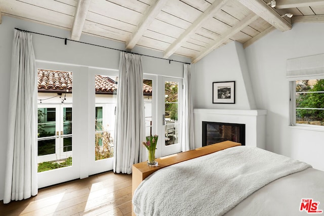 bedroom with hardwood / wood-style flooring, vaulted ceiling with beams, a fireplace, access to outside, and wooden ceiling