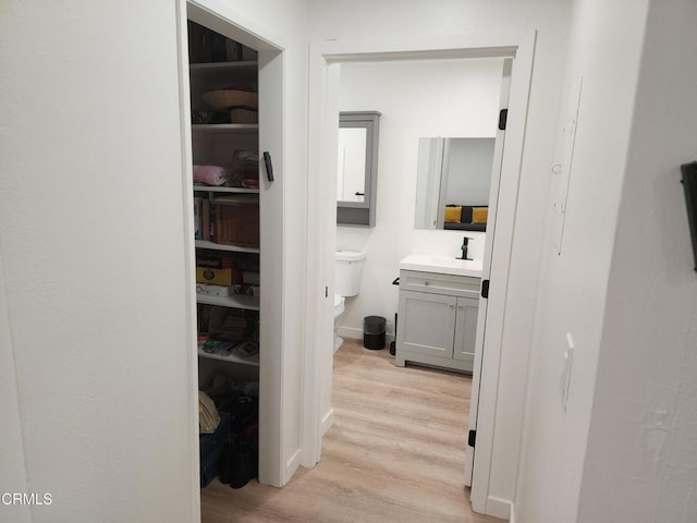 corridor with sink and light wood-type flooring