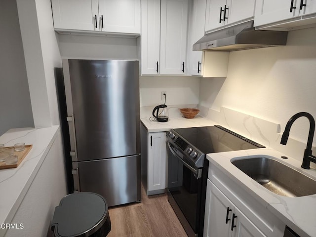 kitchen with sink, stainless steel fridge, black electric range, light stone countertops, and white cabinets