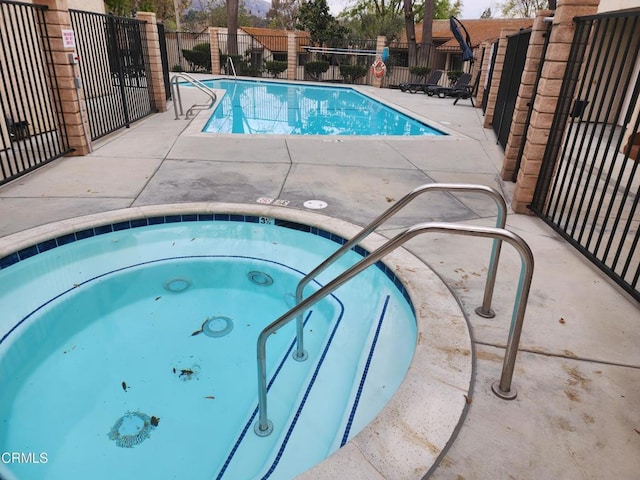 pool featuring a patio, fence, and a hot tub