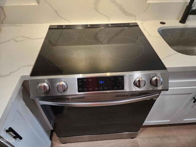 details with tasteful backsplash, electric stove, a sink, and light stone counters