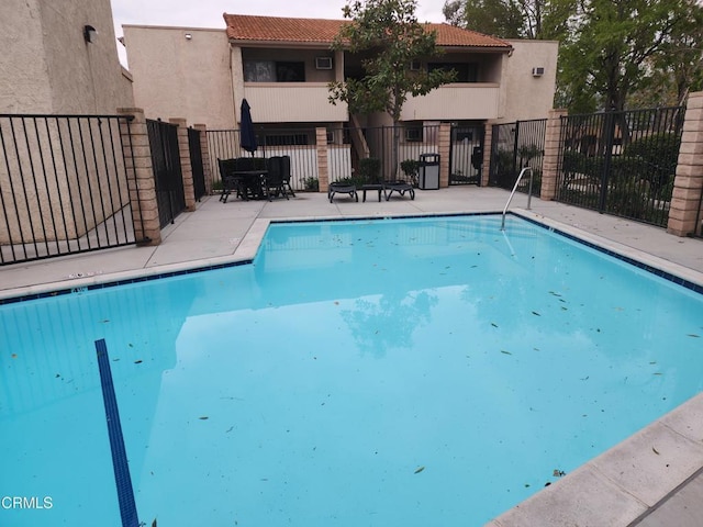 pool with a patio and fence