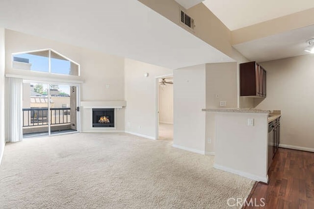 unfurnished living room with dark colored carpet, vaulted ceiling, and ceiling fan