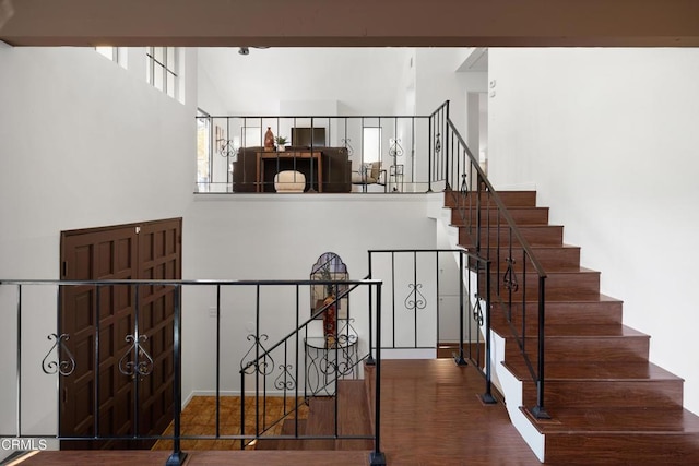 stairway featuring hardwood / wood-style floors and a towering ceiling