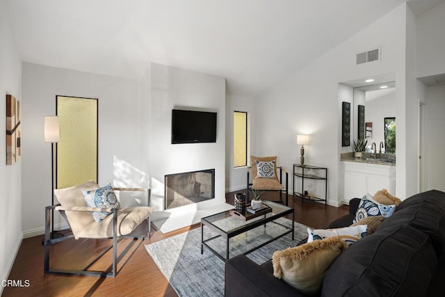 living room featuring vaulted ceiling, dark wood-type flooring, and indoor wet bar