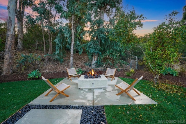 patio terrace at dusk with a fire pit and a lawn