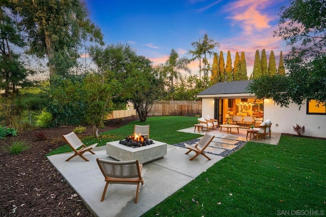 patio terrace at dusk featuring a lawn and an outdoor living space with a fire pit