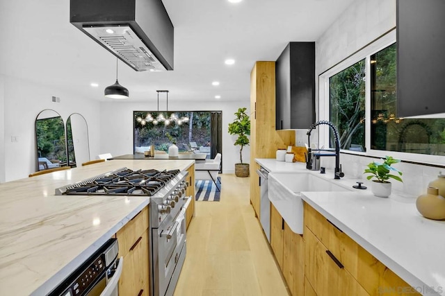 kitchen featuring sink, light stone counters, decorative light fixtures, light hardwood / wood-style flooring, and stainless steel appliances