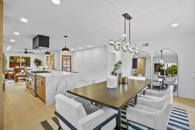 dining area featuring plenty of natural light, ceiling fan with notable chandelier, and light wood-type flooring