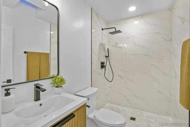 bathroom with vanity, toilet, and a tile shower