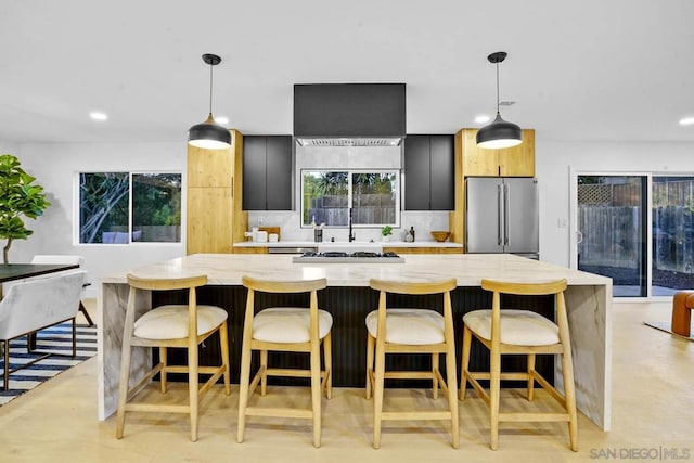 kitchen featuring decorative backsplash, appliances with stainless steel finishes, decorative light fixtures, and a breakfast bar area