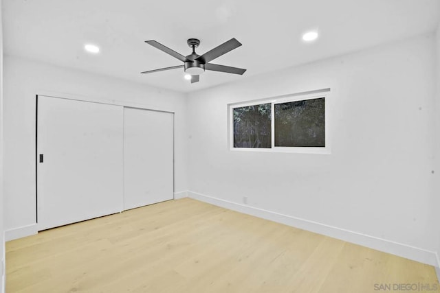 unfurnished bedroom with light wood-type flooring, ceiling fan, and a closet