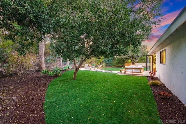 yard at dusk featuring an outdoor living space and a patio