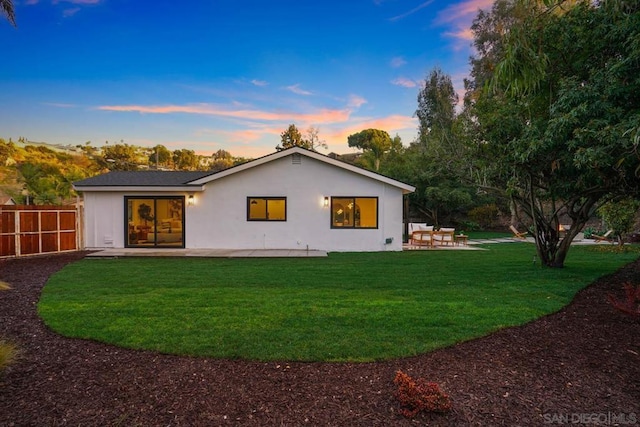 back house at dusk with a yard and a patio area