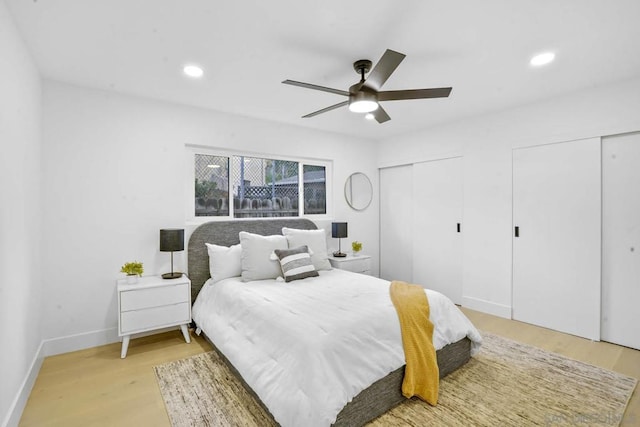 bedroom with multiple closets, ceiling fan, and light wood-type flooring