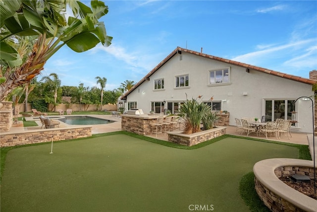 rear view of property with a fenced in pool, a patio area, and an outdoor bar