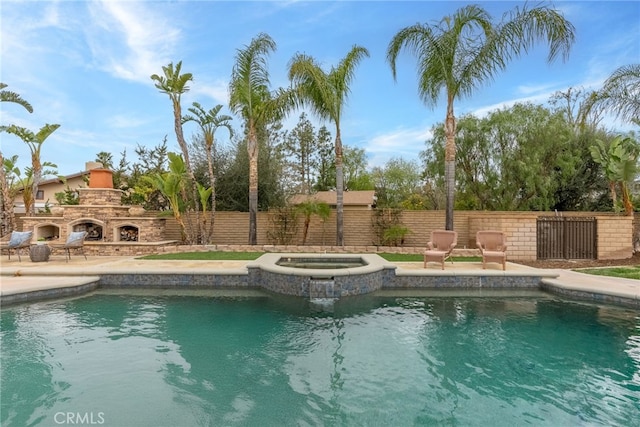 view of swimming pool featuring a patio, an outdoor stone fireplace, and an in ground hot tub