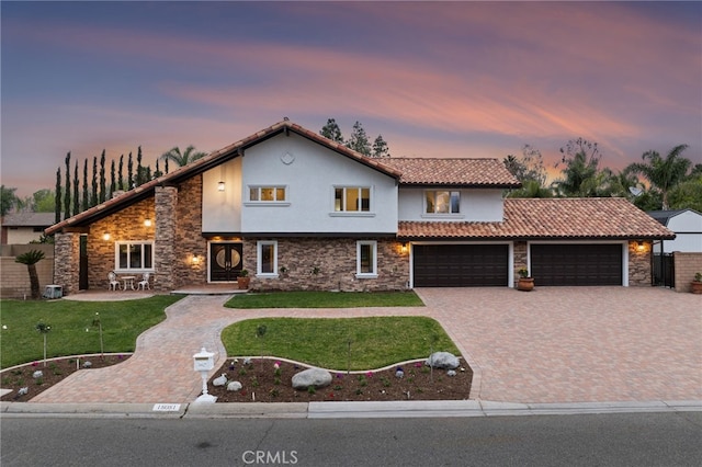 view of front of house featuring a yard, central air condition unit, and a garage