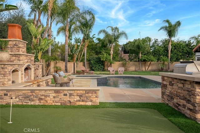 view of swimming pool with grilling area, a patio, an outdoor kitchen, and an outdoor stone fireplace