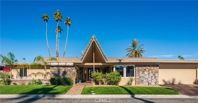 view of front of property featuring an attached garage, stone siding, concrete driveway, stucco siding, and a front yard