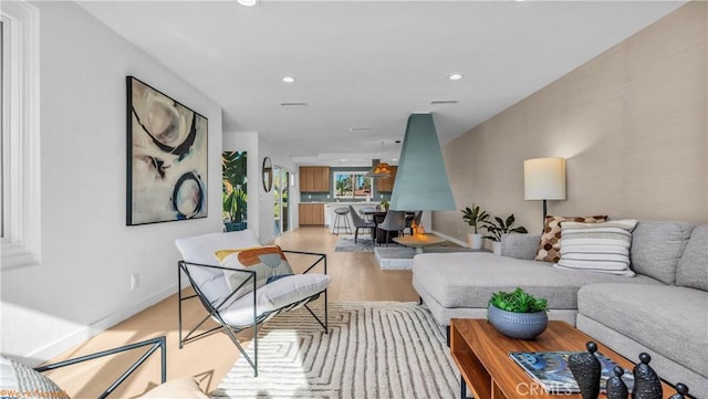 living area featuring light wood-style floors, baseboards, and recessed lighting