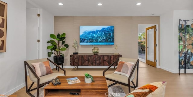 living area with baseboards, wood finished floors, and recessed lighting