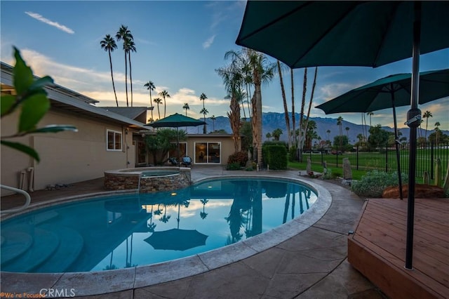 view of pool featuring an in ground hot tub and a deck with mountain view