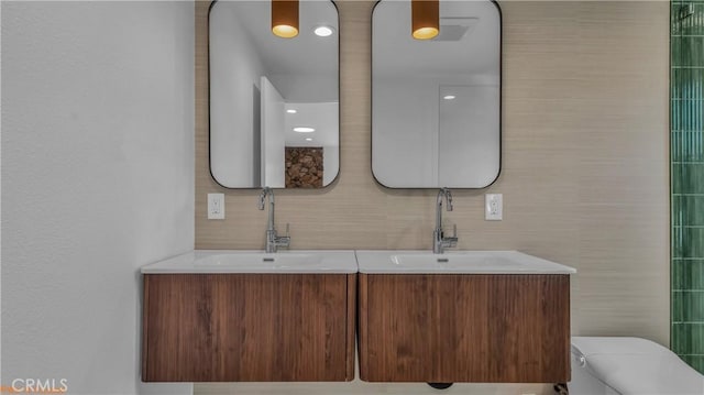 full bath with a sink, tile walls, and double vanity