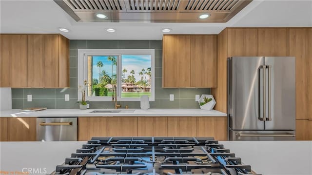 kitchen with modern cabinets, appliances with stainless steel finishes, extractor fan, and light countertops