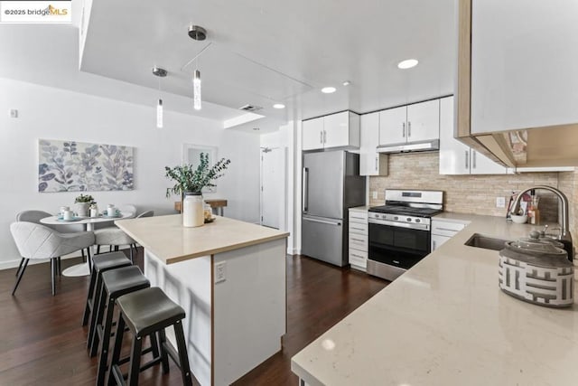 kitchen with a breakfast bar, sink, stainless steel appliances, decorative backsplash, and white cabinets