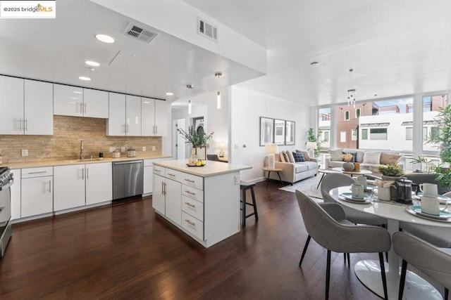 kitchen featuring stainless steel dishwasher, a kitchen breakfast bar, a center island, and white cabinets