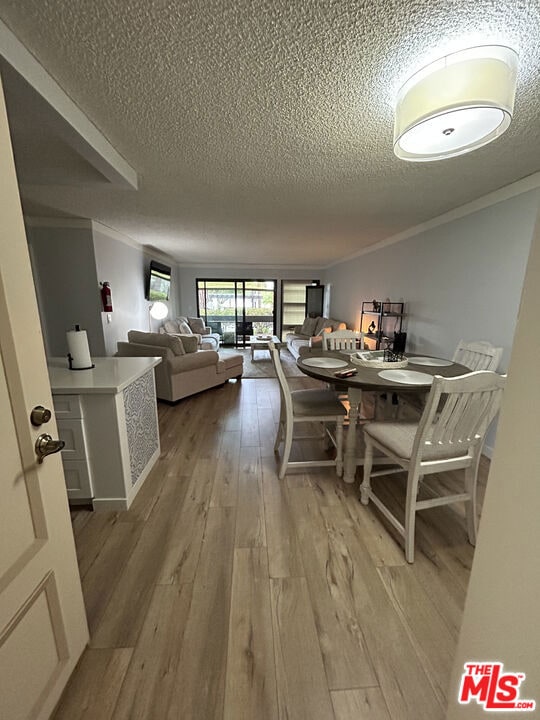 dining room featuring ornamental molding, hardwood / wood-style floors, and a textured ceiling