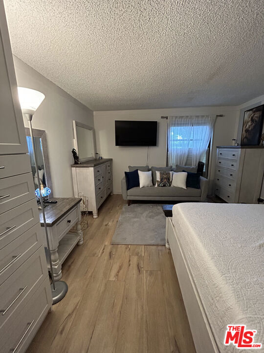 bedroom with a textured ceiling and light wood-type flooring