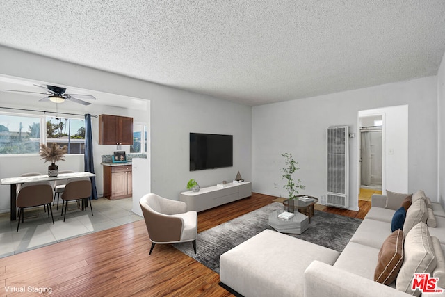 living room with ceiling fan, light hardwood / wood-style flooring, and a textured ceiling