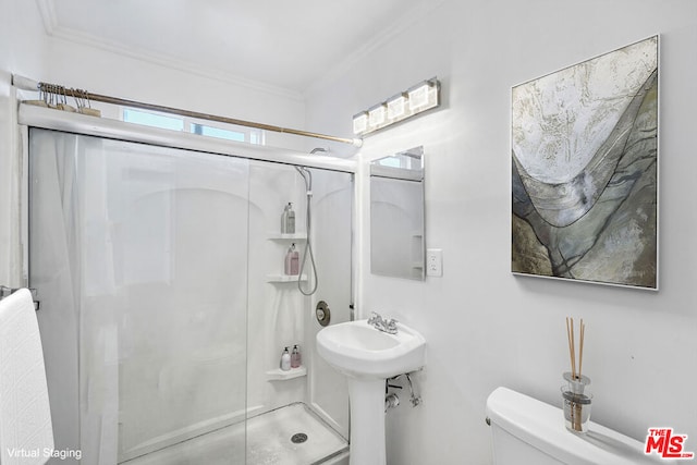 bathroom with ornamental molding, toilet, and a shower with shower door