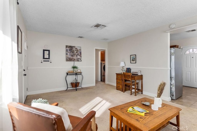 carpeted living room featuring washer / dryer and a textured ceiling