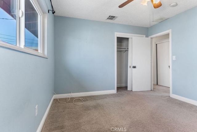 unfurnished bedroom with ceiling fan, light colored carpet, a textured ceiling, and a closet