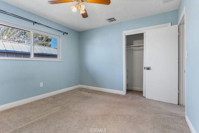 unfurnished bedroom with ceiling fan, light colored carpet, a textured ceiling, and a closet