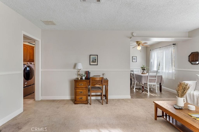 living room with washer / clothes dryer, light colored carpet, and a textured ceiling