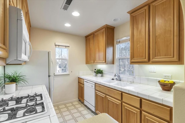 kitchen with sink, tile counters, and white appliances