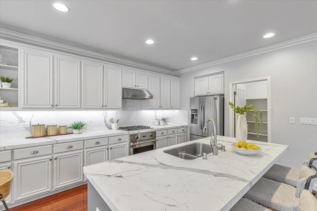 kitchen featuring sink, a kitchen bar, stainless steel appliances, light stone countertops, and a center island with sink