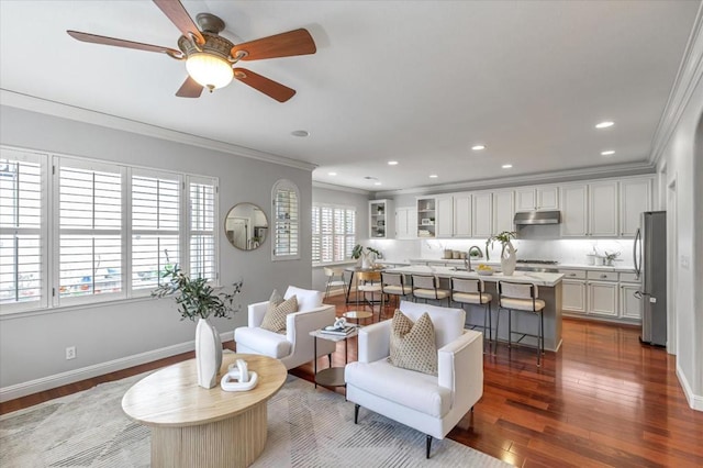 living room with dark wood-type flooring, ornamental molding, and sink