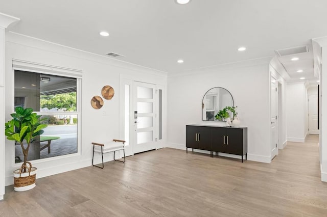 foyer entrance with light hardwood / wood-style flooring and ornamental molding