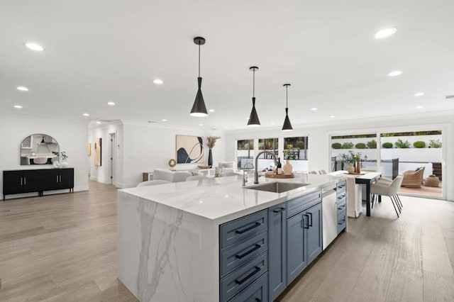 kitchen featuring sink, crown molding, hanging light fixtures, and a center island with sink