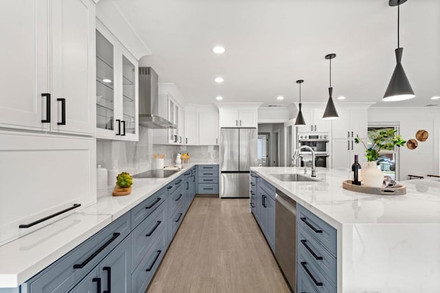 kitchen with a large island, pendant lighting, wall chimney exhaust hood, and appliances with stainless steel finishes